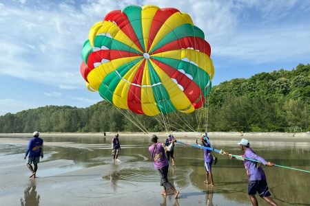 a group of people running in water with a parachute