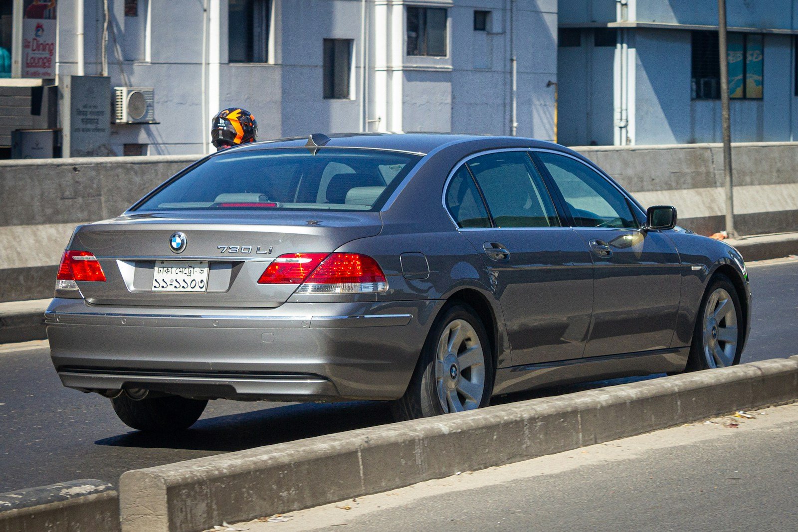 A silver car driving down a street next to tall buildings